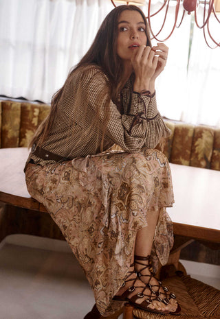A woman sits on a wooden bench in a warm