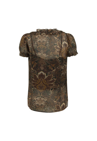  wearing a sheer brown lace short-sleeve top and beige wide-leg patterned pants. Large arched windows