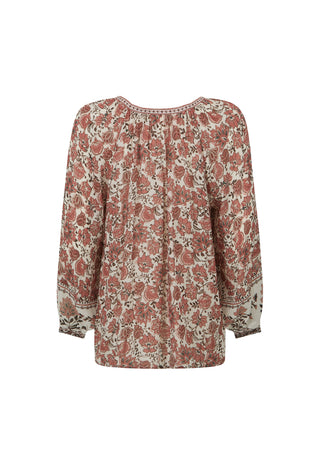 A woman modeling a long-sleeve bohemian-style blouse with a rust-brown and cream floral pattern