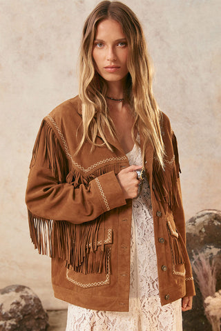Woman wearing a brown fringed jacket against a neutral background